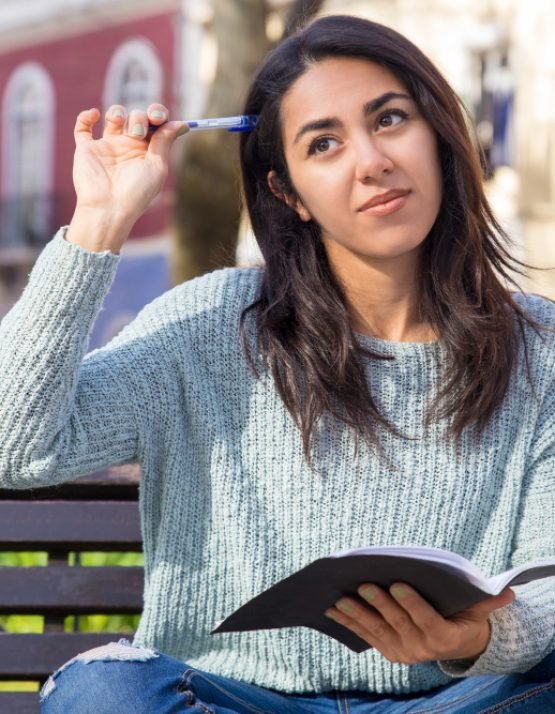 pensive-woman-scratching-head-with-pen-sitting-bench